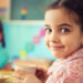 Cute little hispanic girl drinking milk at school