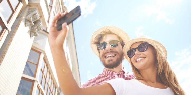 Happy girl making selfie with her boyfriend near by