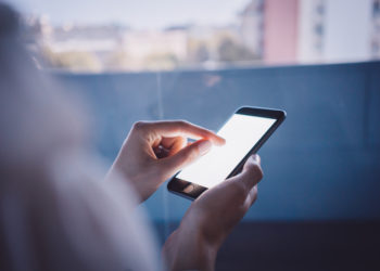 Smartphone holding in female hand on the blured background