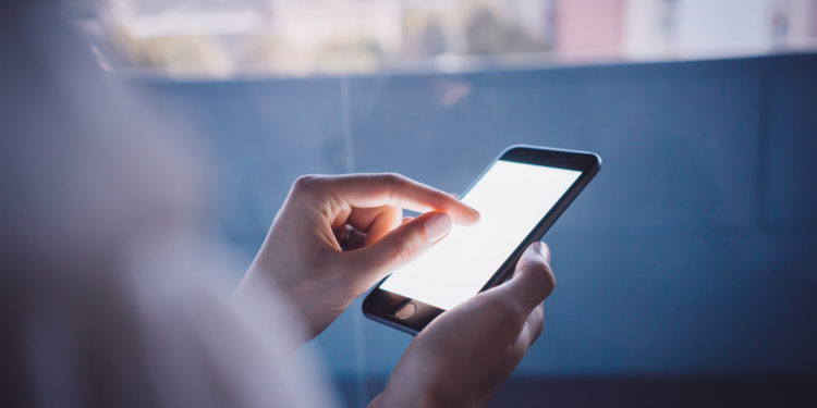 Smartphone holding in female hand on the blured background