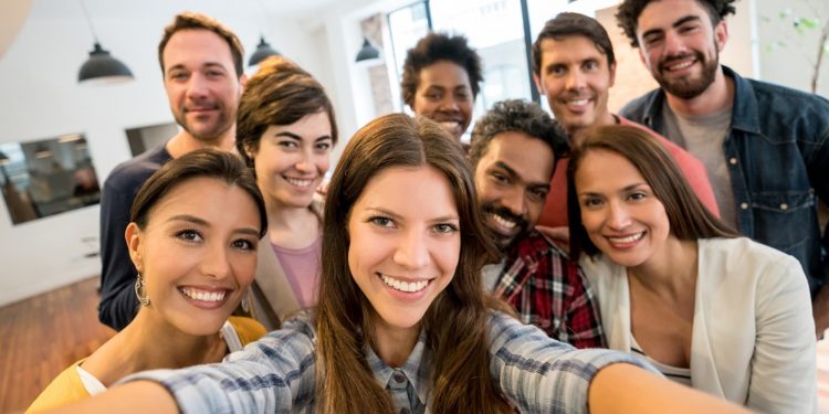 Portrait of a happy group of Latin American coworkers taking a selfie at a creative office