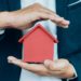 Business man hand hold the house model  saving small house. House insurance