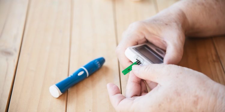 Old lady is testing blood sugar level using blood sugar test kid set - people with medical equipment concept