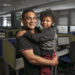 Fahiem Abrahams, 37, holds his son Fawad, 4, for a portrait taken at the Wonga call centre where Fahiem works in Cape Town, South Africa on 7 May 2019. Fawad, who lives with autism, communicates primarily through musical intonation rather than words. “For someone who’s non-verbal, he’s very vocal,” Fahiem says. “A year and a half ago he was basically mute. Now anything he says is music to my ears. He sings all the time, but I can’t make out what he’s saying.” In January 2019, Fawad began attending Alpha School for Learners with Autism. In the months since then, he has made tremendous strides forward, passing developmental milestones that his parents worried he might never reach. While Fawad’s enrollment at Alpha School has been a life-changing event, it has also created new challenges for the family. The school is located far from Fahiem’s office and his family's home, requiring a two-hour commute each morning. But Fahiem says that “just being there for your kids” is the most important part of being a dad.

Fawad, age 4, wanders into the room, his thick mop of long, loose curls swaying with each small footfall, with a melodic string of sounds tumbling from his smiling lips. “For someone who’s non-verbal, he’s very vocal,” says Fawad’s father, Fahiem Abrahams, 37. “A year and a half ago he was basically mute. Now... he sings all the time, but I can’t make out what he’s saying.” Fawad, who lives with autism, is the middle of three children. His family lives in Bonteheuwel, Western Cape, South Africa. “If you go to an autism workshop, you’ll see three fathers and 40 mothers,” Fahiem says. “I don’t know why fathers are so disengaged.”

Taheera, Fahiem's wife, interjects: “Fathers struggle to accept (autism), where mothers have no choice but to accept. It’s a maternal value to accept, where fathers don’t want to give up their dreams.”

Fahiem nods his head in agreement.At first, Faheim and Taheera felt helpl
