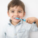 A smiley boy cleans a teeth isolated on grey background
