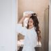 Beautiful smiling woman curling long hair using curling iron in the bath