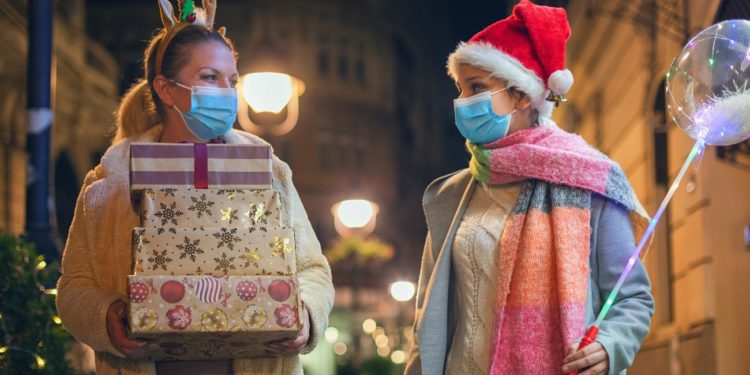 Young family having fun while walking and shopping Christmas gifts in the city. They wears a protective mask to protect from corona virus COVID-19.