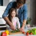 Handsome man and his little cute daughter are cooking on kitchen. Making salad. Healthy lifestyle concept