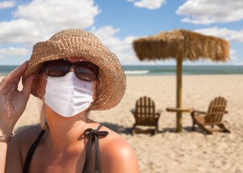 Vacationing Woman Wearing Face Mask on Sandy Beach..
