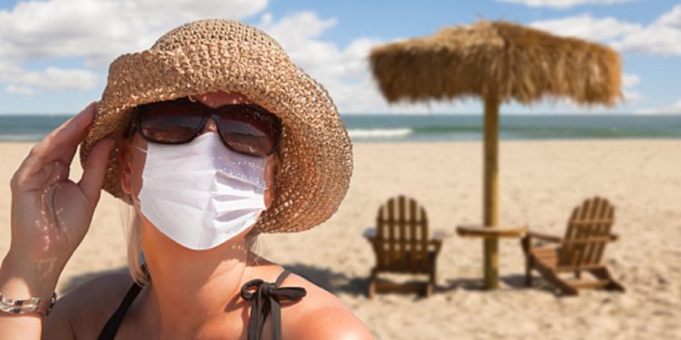 Vacationing Woman Wearing Face Mask on Sandy Beach..