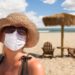 Vacationing Woman Wearing Face Mask on Sandy Beach..