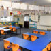 Empty tables and chairs in class with whiteboard and educational equipment. Artwork hanging up on clothes line inside