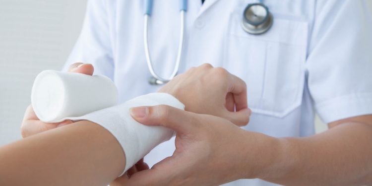 Closeup and selective focus on applying bandage onto patient's hand.