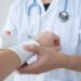 Closeup and selective focus on applying bandage onto patient's hand.