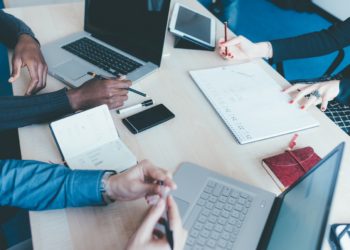 Top view of an office desk with a group of people working using technological devices - work, business, teamwork concept