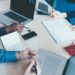 Top view of an office desk with a group of people working using technological devices - work, business, teamwork concept
