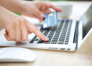 Hands holding a credit card and using laptop computer for online shopping