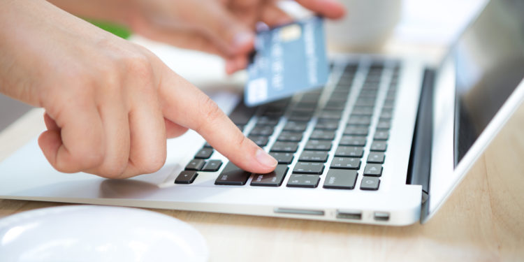 Hands holding a credit card and using laptop computer for online shopping
