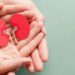 Adult and child holding kidney shaped paper on textured blue background, world kidney day, National Organ Donor Day, charity donation concept