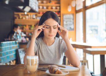 Young female sitting in a cafe indoors rest sick