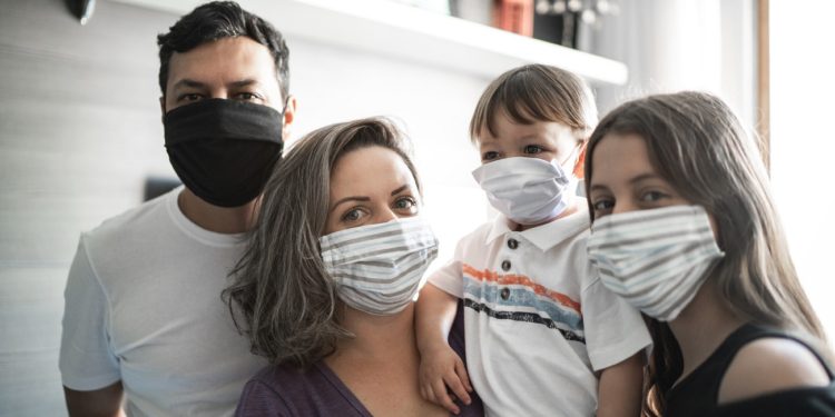 Portrait o family using face mask at home