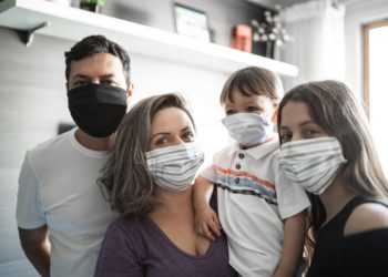 Portrait o family using face mask at home