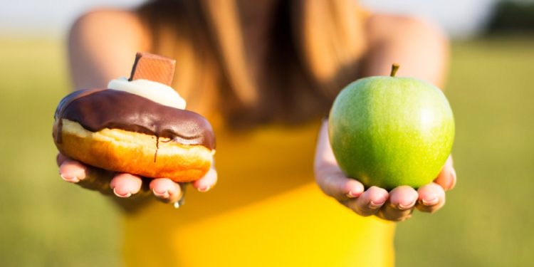 Woman choosing between healthy fruits and donut. Healthy lifestyle or nutrition concept