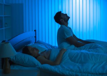 The man sit on the bed with an insomnia near woman. night time