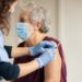 General practitioner vaccinating old patient in private clinic with copy space. Doctor giving injection to senior woman at hospital. Nurse holding syringe and using cotton before make Covid-19 or coronavirus vaccine.