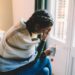 Woman with temperature staying home wrapped in scarf and drinking hot tea