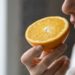 Sick woman trying to sense smell of half fresh orange, has symptoms of Covid-19, corona virus infection - loss of smell and taste. One of the main signs of the disease.