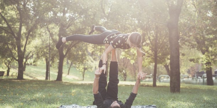 Sportive couple doing yoga outdoor park - Personal trainer and sportive woman training outdoor