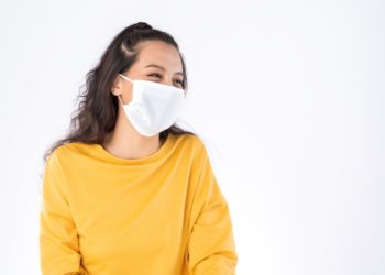 Young happy Asian woman wearing hygienic mask to prevent infection corona virus Air pollution pm2.5 she wearing a yellow sweater shoot in shot isolated on white background