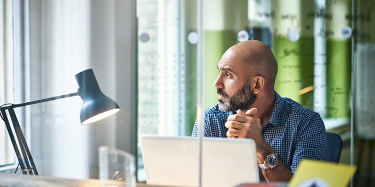 Businessman sitting in front of laptop in modern office.