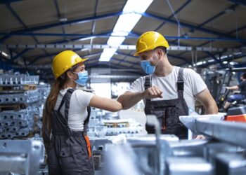 Factory workers greeting each others with elbows during corona virus pandemic.