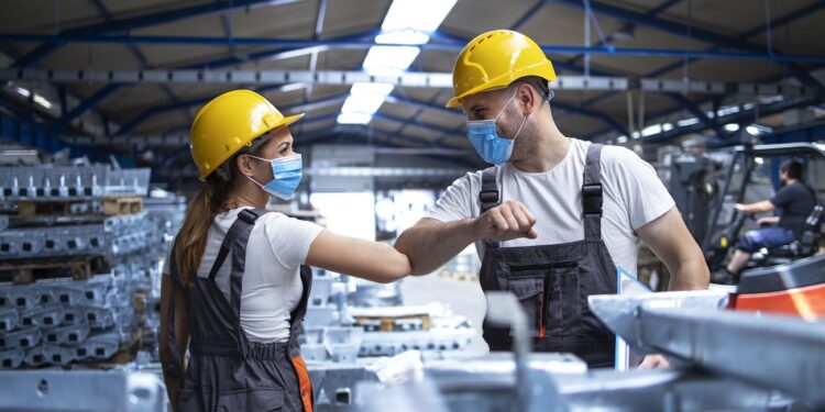 Factory workers greeting each others with elbows during corona virus pandemic.