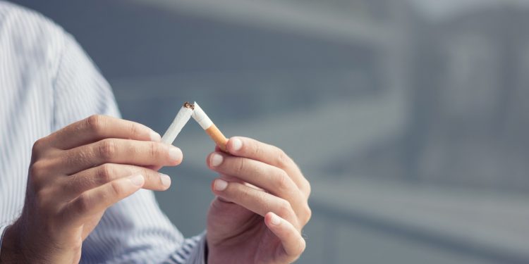 Man breaking cigarette in half. Stop smoking concept.