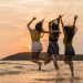 Group of three Asian young women jumping on beach, friends happy relax having fun playing on beach near sea when sunset in evening. Lifestyle friends travel holiday vacation on beach summer concept.
