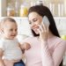 Happy motherhood. Cheerful mom bonding with baby and talking on cellphone, panorama