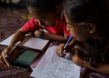 July 24, 2020 - Phnom Penh (Cambodia). Nha Nha helps her smaller sister Sopheap with her home-works using a live streaming lesson. The school has been using streaming apps to provide essential teacher-student interaction and creating a series of physical training exercises. Using Google classroom, Telegram and Facebook Groups, as well as Messenger, allow students to continue studying from the safety of home. To ensure students have suitable equipment to learn online, ISF loans tablet computers to those in need. Subsidies are also available for students who struggle to afford internet service. © Thomas Cristofoletti / UNICEF