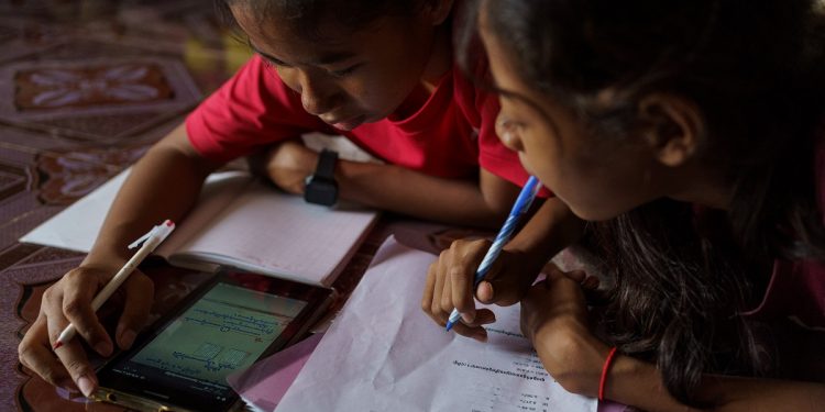 July 24, 2020 - Phnom Penh (Cambodia). Nha Nha helps her smaller sister Sopheap with her home-works using a live streaming lesson. The school has been using streaming apps to provide essential teacher-student interaction and creating a series of physical training exercises. Using Google classroom, Telegram and Facebook Groups, as well as Messenger, allow students to continue studying from the safety of home. To ensure students have suitable equipment to learn online, ISF loans tablet computers to those in need. Subsidies are also available for students who struggle to afford internet service. © Thomas Cristofoletti / UNICEF