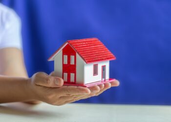 Human hands holding model of dream house, loans and investments concept