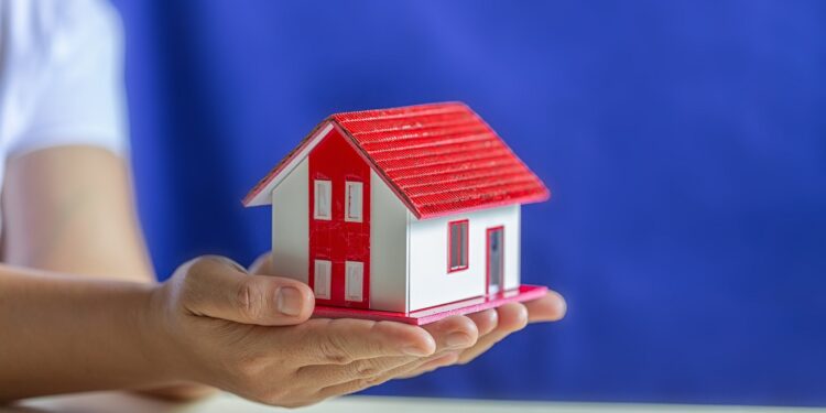 Human hands holding model of dream house, loans and investments concept
