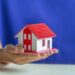 Human hands holding model of dream house, loans and investments concept