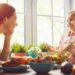 Happy family having dinner together sitting at the rustic wooden table. Mother and her daughter enjoying family dinner together.