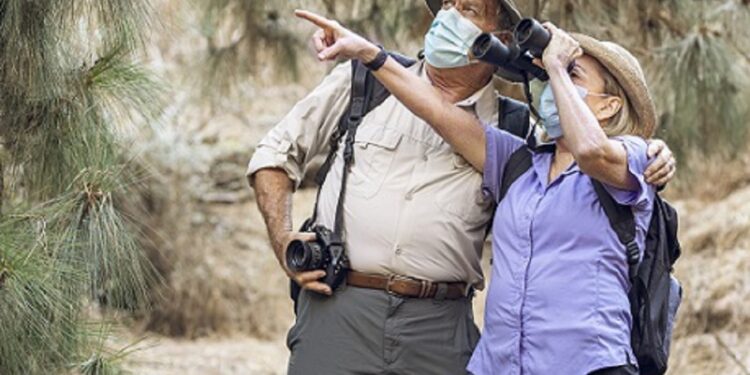 Couple appreciating the beauty of nature with binoculars during the new normal