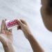 Close-up of young woman's hand holding birth control pills