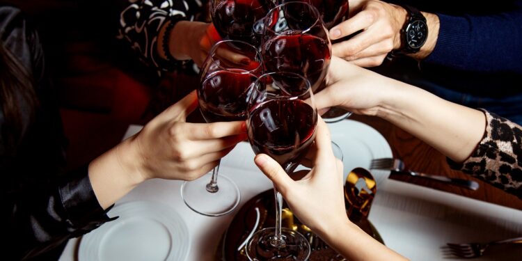 raised glasses of red wine and chocolate cake
