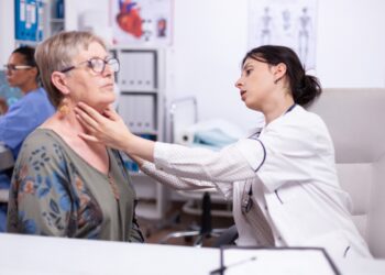 Young medic palpating neck of senior woman, elderly patient visiting doctor at hospital checking thyroid throat touching health at clinic. Healthcare specialist, medicare, treatment medical concept.