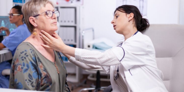 Young medic palpating neck of senior woman, elderly patient visiting doctor at hospital checking thyroid throat touching health at clinic. Healthcare specialist, medicare, treatment medical concept.